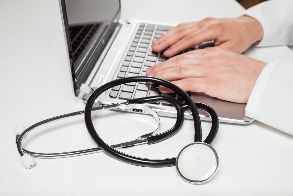 Mãos do médico usando o notebook representando o uso do sistema cis